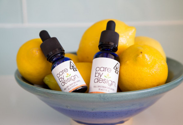 Photo of Care By Design tincture bottles sitting in a bowl full of lemons
